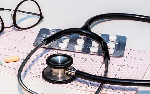 Stethoscope and medication on a heart-rate chart